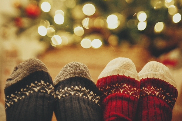 stylish festive socks on couple legs on background of golden beautiful christmas tree with lights