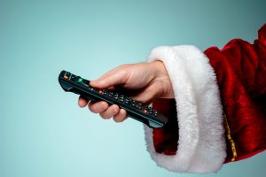 Santa Claus holding tv remote control on blue background