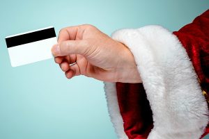 Santa Claus hand holding a credit card on blue studio background