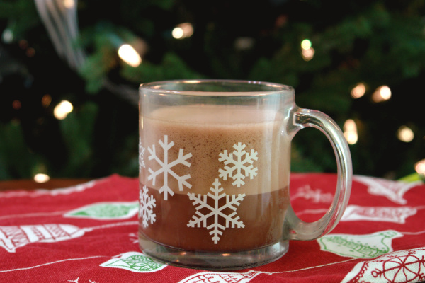 oat milk hot chocolate in snowflake mug in front of Christmas tree