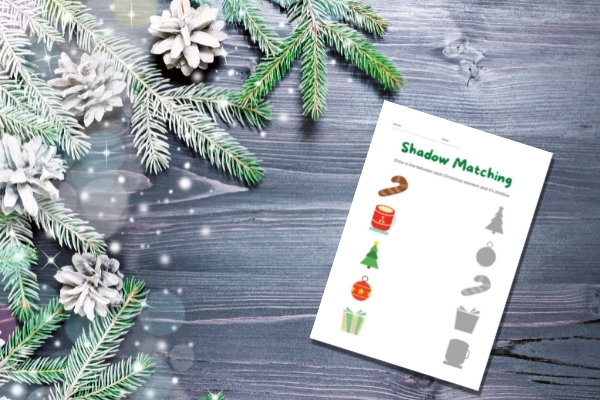 christmas worksheet on gray wooden table with evergreen pieces on table