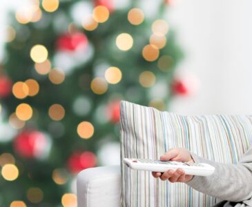 person pointing remote at tv with christmas tree in background