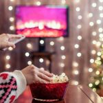 Christmas movie on tv with woman eating popcorn and changing the channel