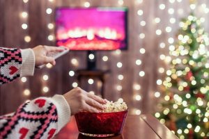 Christmas movie on tv with woman eating popcorn and changing the channel