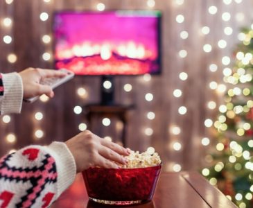 Christmas movie on tv with woman eating popcorn and changing the channel