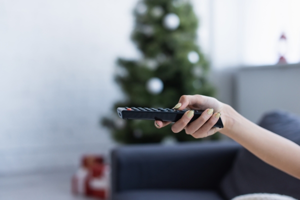 christmas tree in background with person holding remote