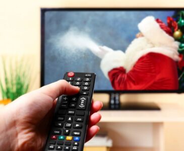 person holding remote in front of tv with Santa on screen