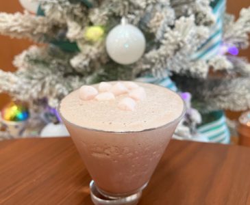 frozen hot chocolate martini in martini glass with mini marshmallows on top in front of flocked christmas tree