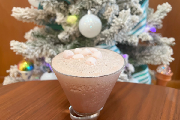 frozen hot chocolate martini in martini glass with mini marshmallows on top in front of flocked christmas tree