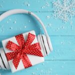 blue table with snowflakes and white headphones over a white gift with red ribbon