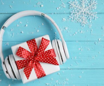 blue table with snowflakes and white headphones over a white gift with red ribbon