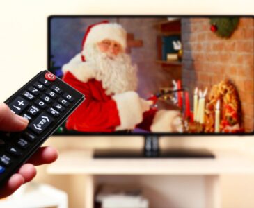 person pointing remote at tv with Santa on tv
