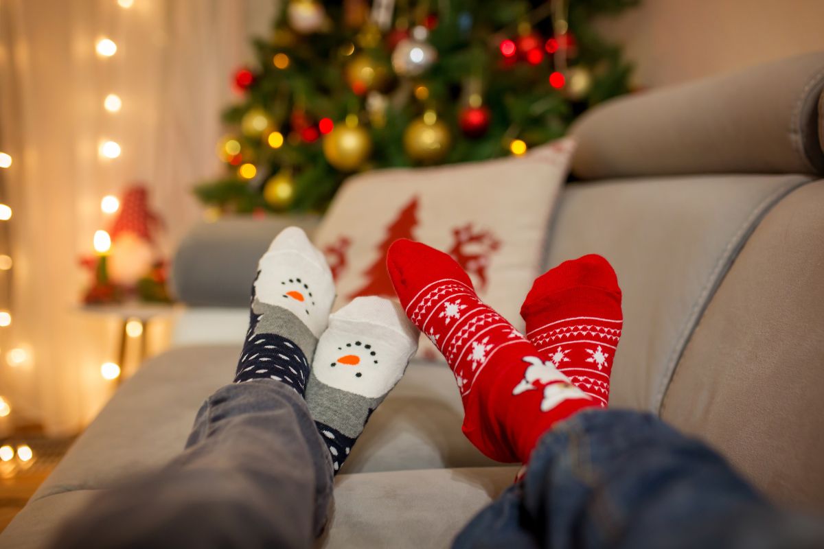 couple's feet in christmas socks on sofa with tree in background