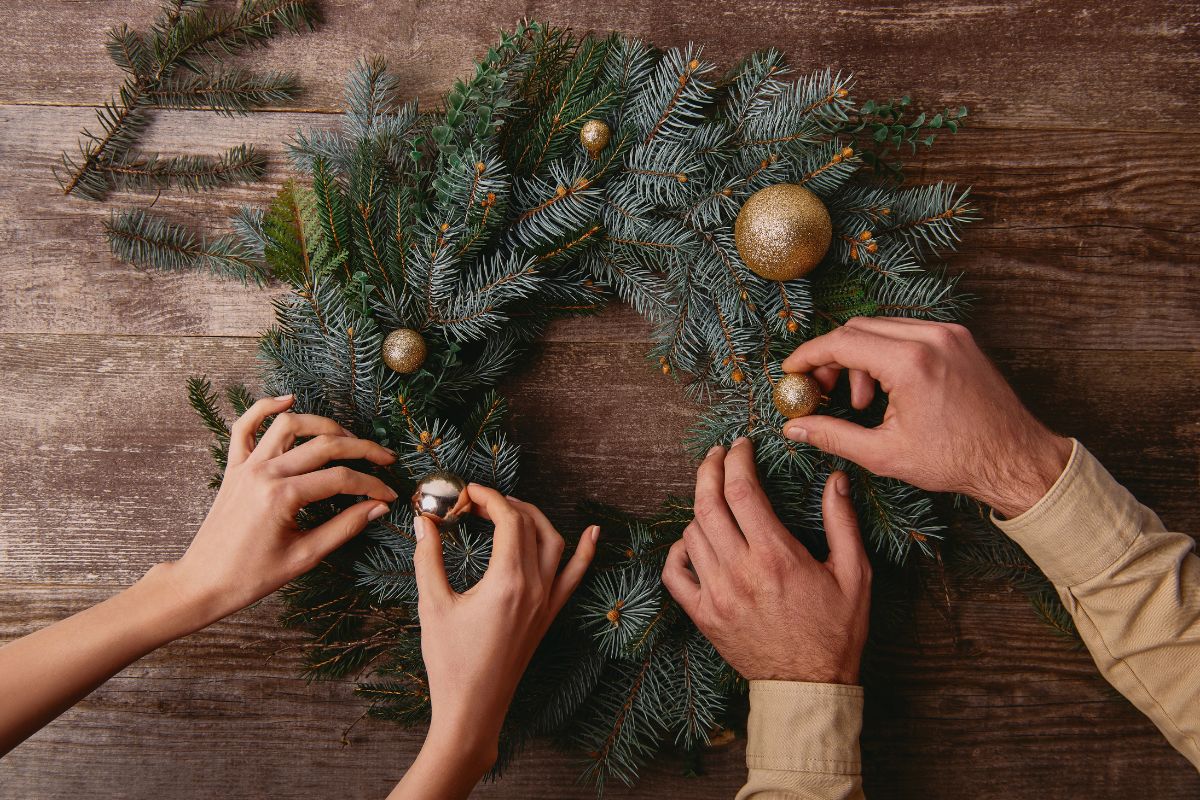 hands of couple decorating a Christmas wreath