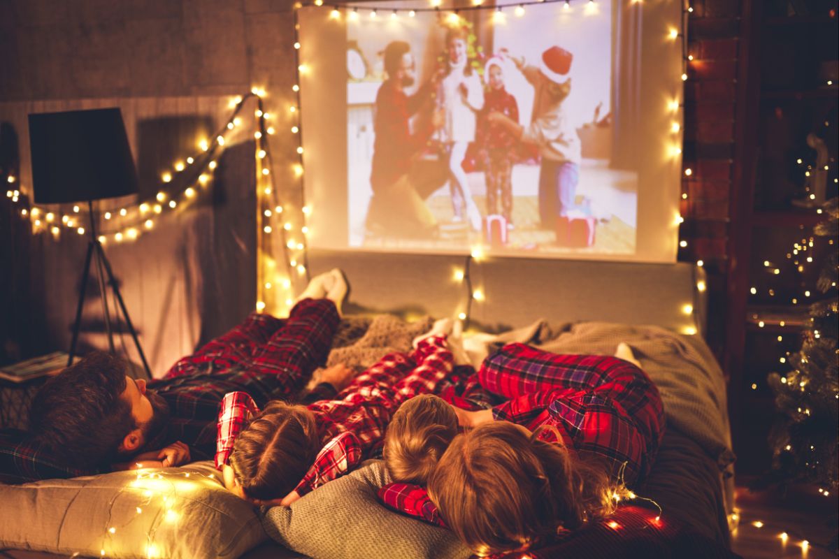 family watching Christmas movie projected on wall with Christmas decorations around